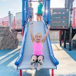 Girl on commercial playground roller slide