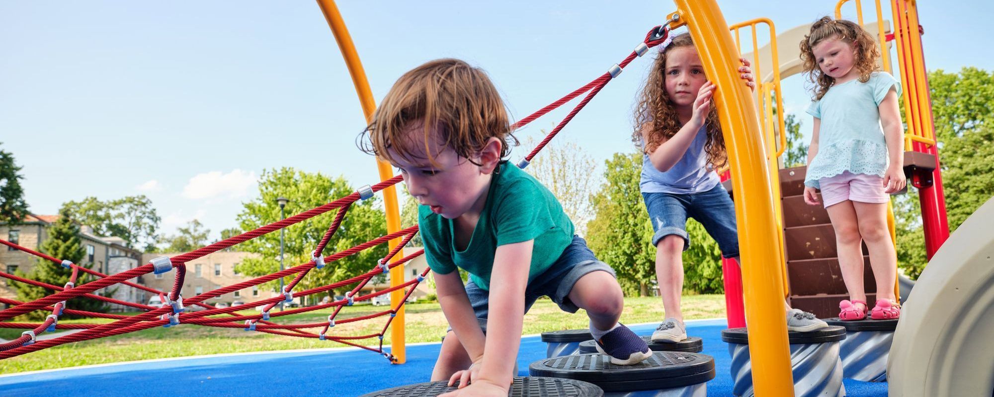 little boy crawling across playground steppers