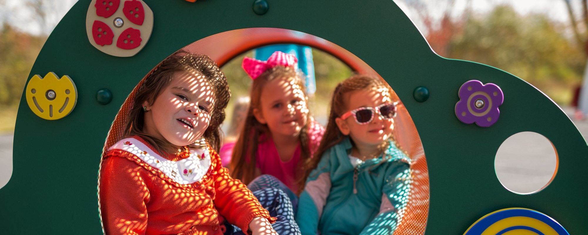 kids sitting in garden crawl tunnel