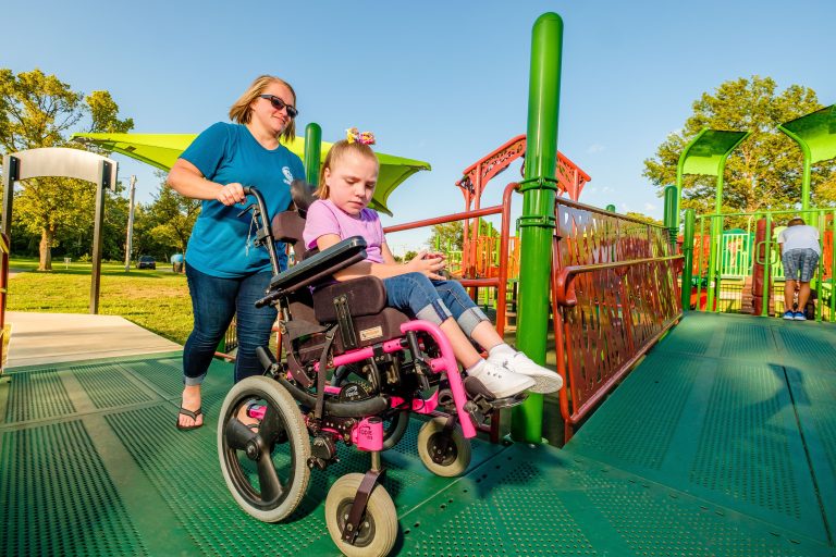girl with wheel chair being pushed on playground