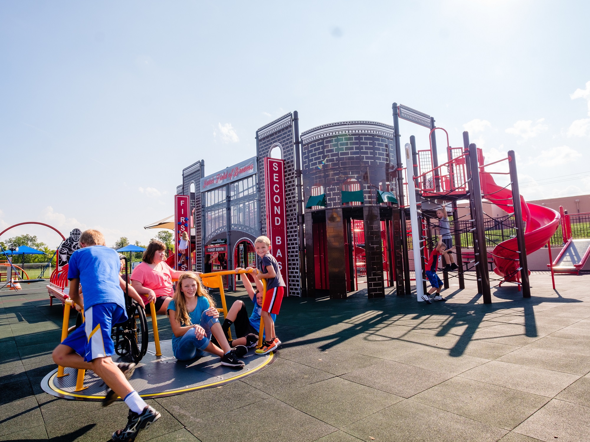 Children sitting on inclusive playground spinner